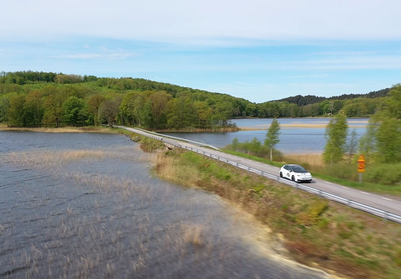 POS Trafikskola - Trafikskolebil som kör i vacker natur mellan två sjöar